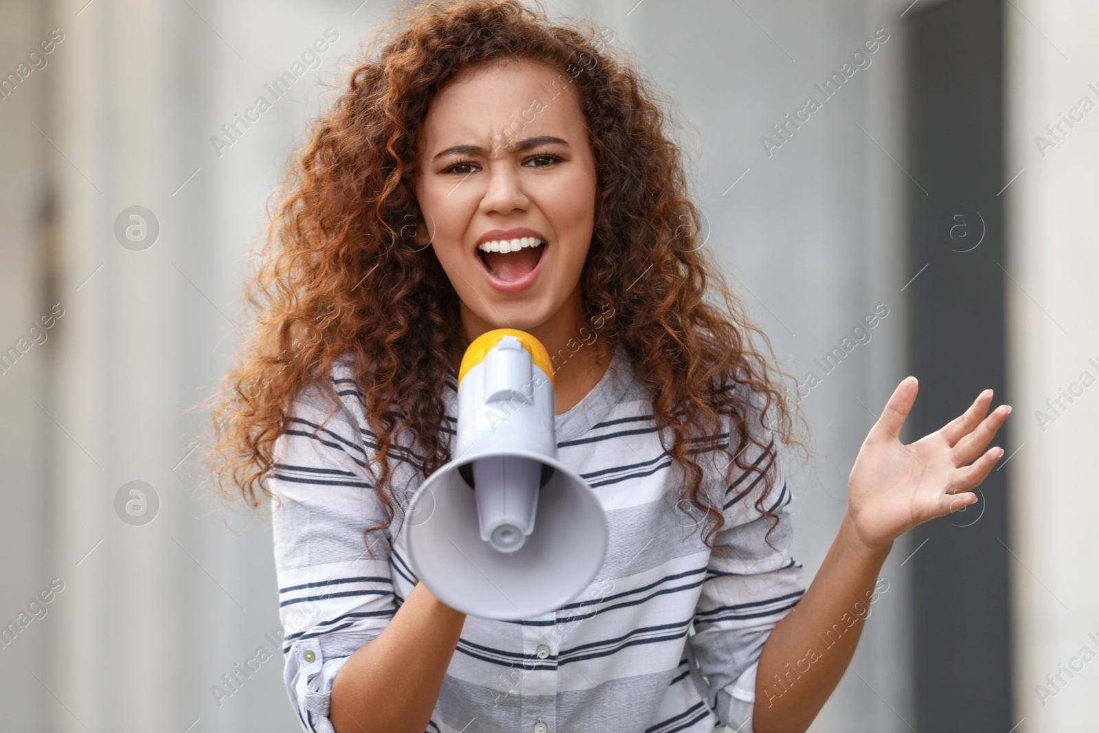 Image of Emotional African American young woman with megaphone outdoors. Protest leader