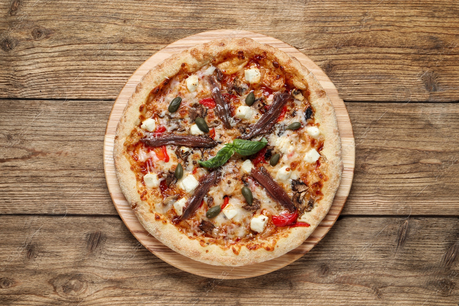 Photo of Tasty pizza with anchovies, basil and olives on wooden table, top view