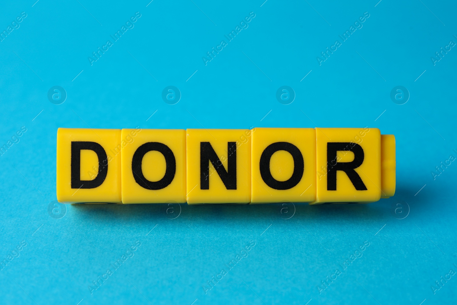 Photo of Word Donor made of cubes on light blue background