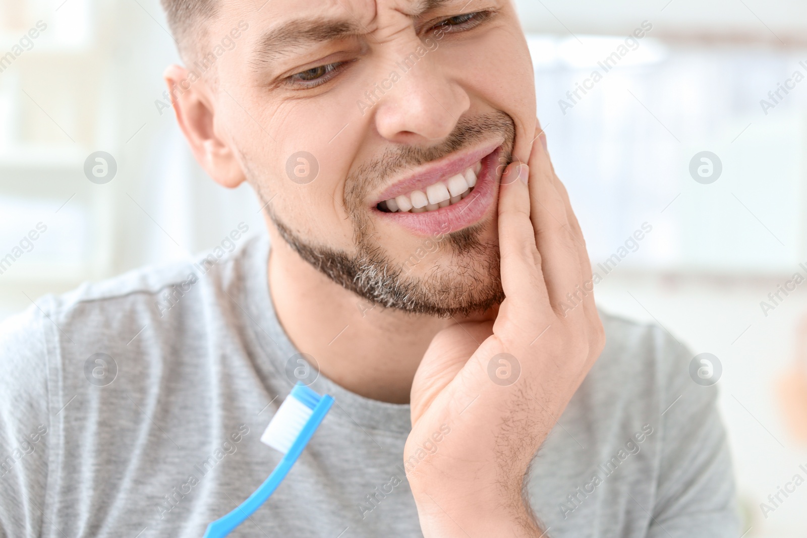 Photo of Young man suffering from toothache indoors