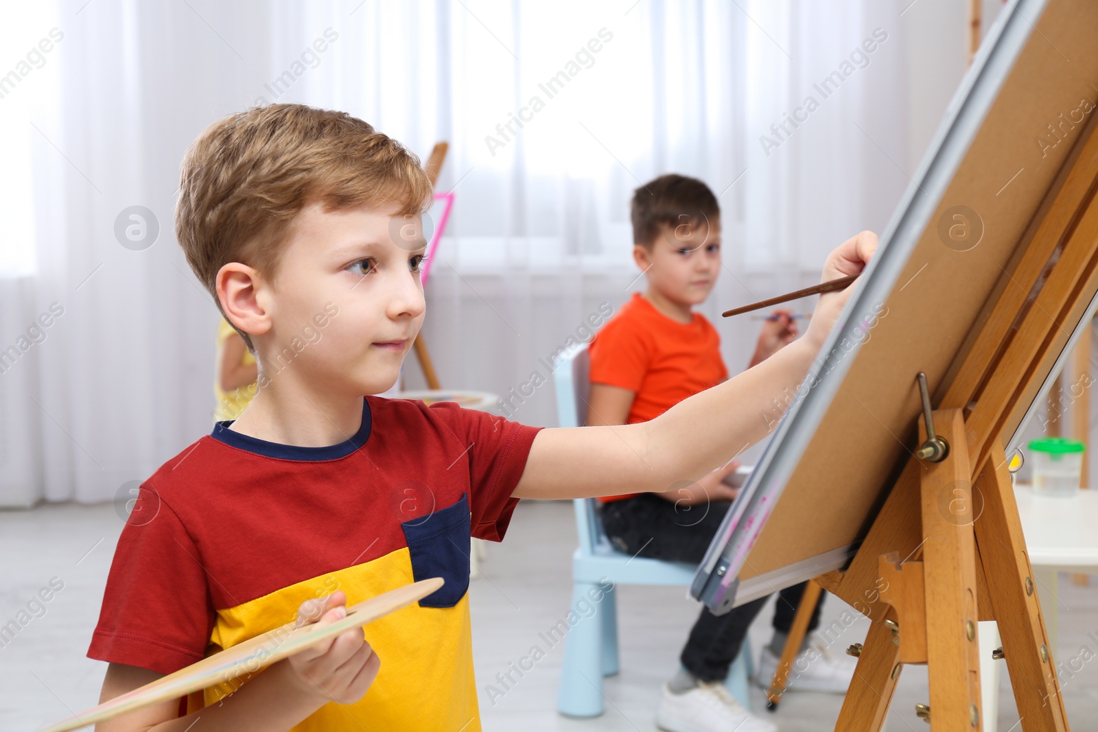 Photo of Cute little child painting during lesson in room