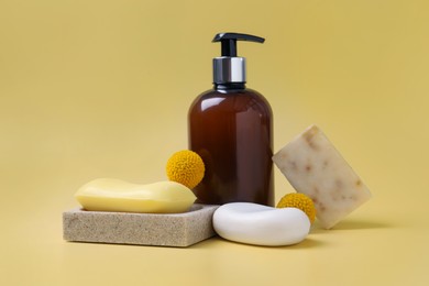 Photo of Soap bars and bottle dispenser on yellow background