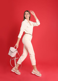 Photo of Beautiful young woman in casual outfit with stylish bag on red background