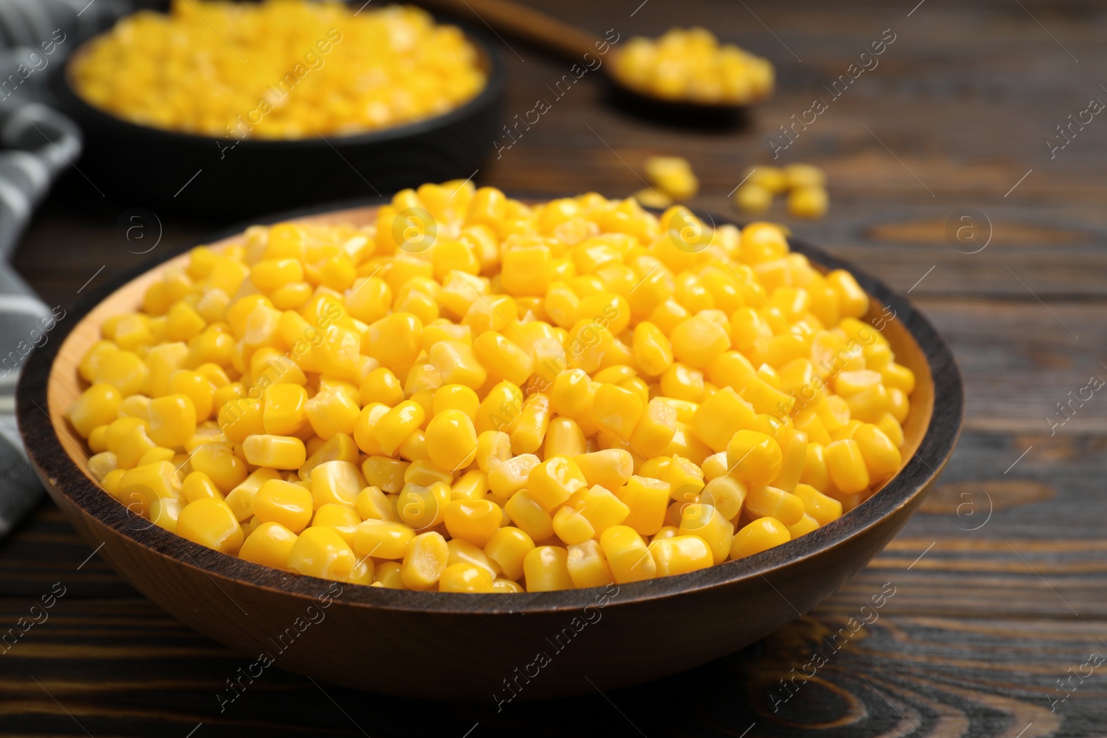 Photo of Delicious canned corn in bowl on wooden table, closeup