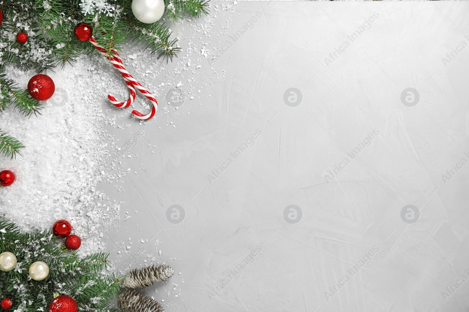 Photo of Christmas decoration with white snow on light grey stone background, flat lay. Space for text