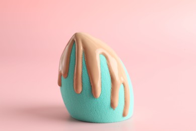 Photo of Makeup sponge with skin foundation on pink background