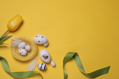 Flat lay composition with festively decorated Easter eggs on yellow background. Space for text