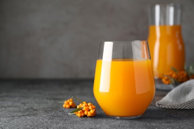 Delicious sea buckthorn juice and fresh berries on grey table. Space for text