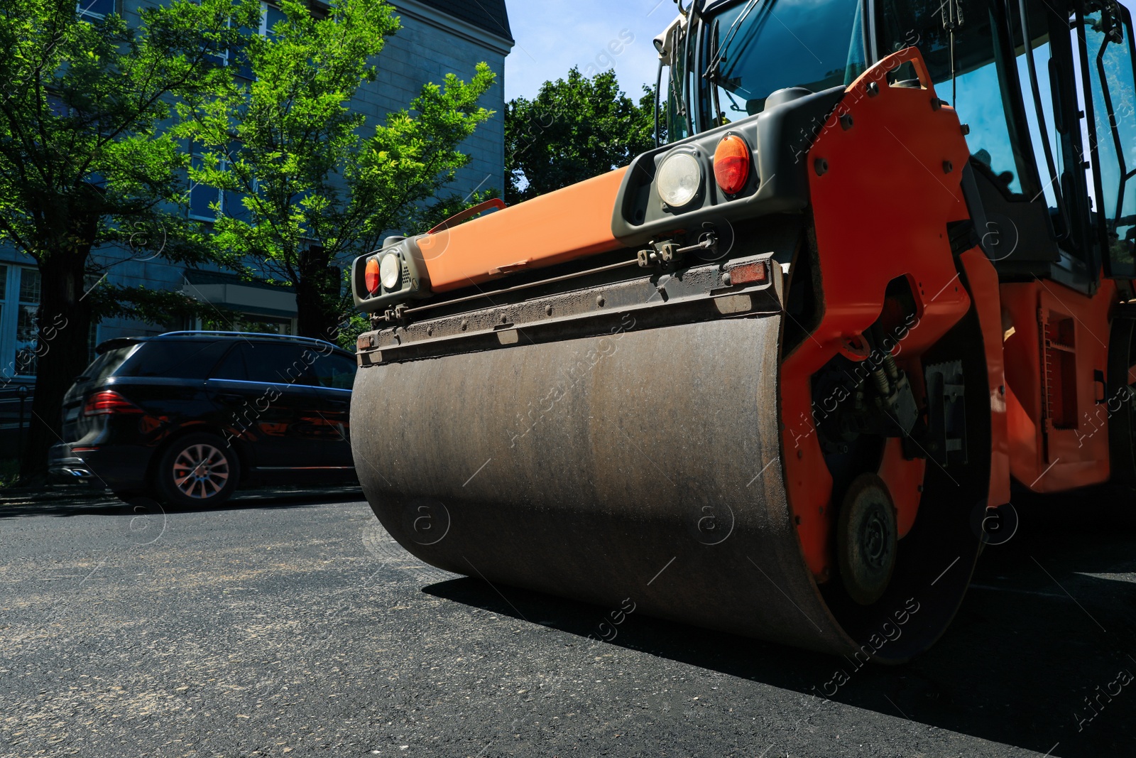 Photo of Roller working on city street, low angle view. Road repairing