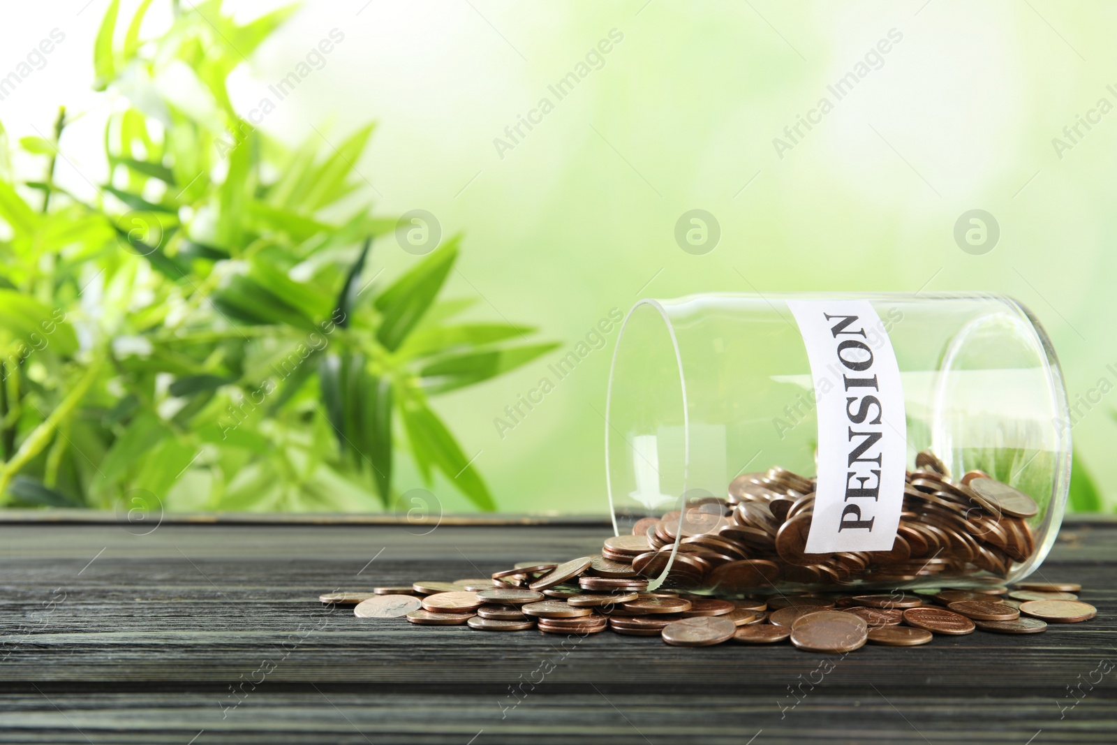 Photo of Glass jar with label PENSION and coins on wooden table. Space for text