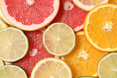 Photo of Different sliced citrus fruits as background, top view