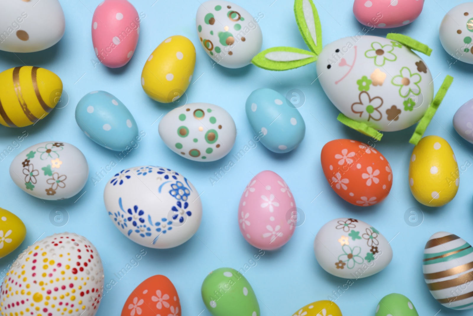Photo of Colorful Easter eggs on light blue background, flat lay