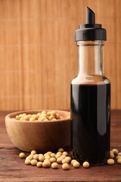 Bottle of soy sauce and soybeans on wooden table