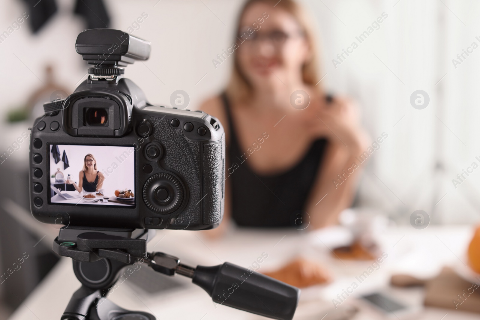 Photo of Food blogger recording video indoors, focus on camera display. Space for text