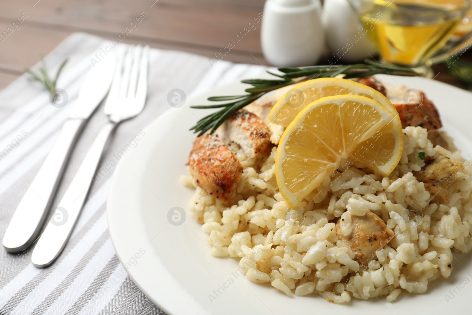 Photo of Delicious chicken risotto with lemon slices on table