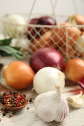 Photo of Fresh onion bulbs, garlic and peppers mix on white wooden table, closeup