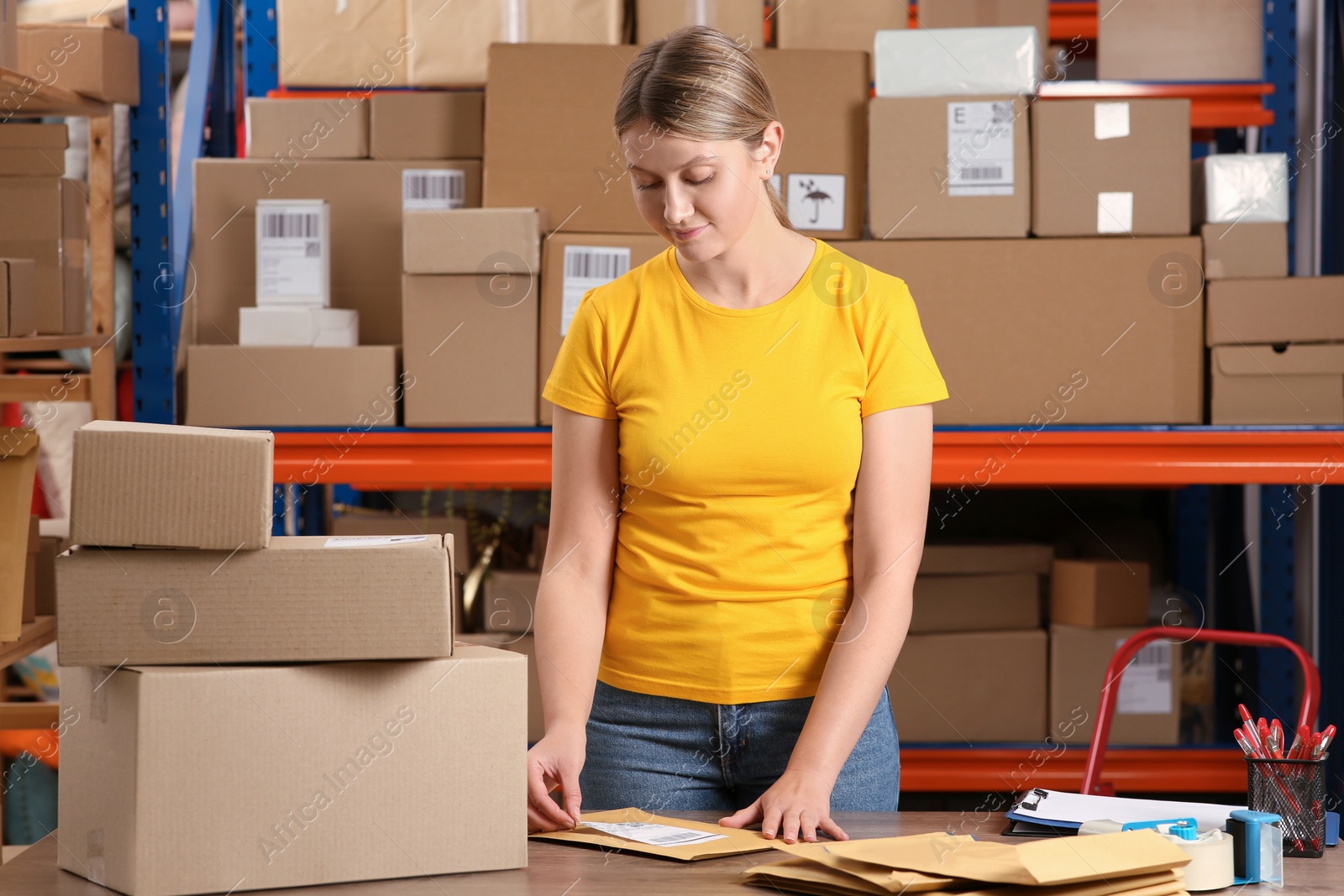 Photo of Post office worker sticking barcode on parcel at counter indoors