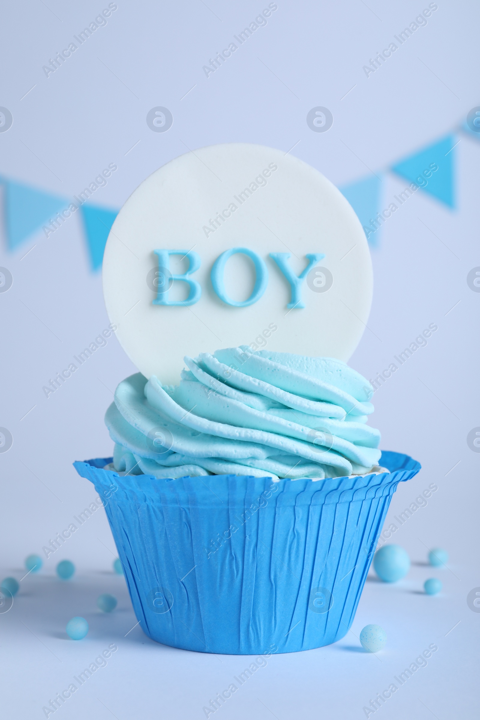 Photo of Beautifully decorated baby shower cupcake for boy with cream and topper on light background