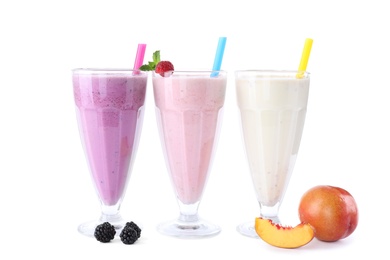 Different fresh tasty milk shakes in glasses with ingredients on white background