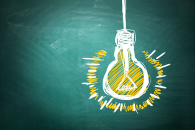 Image of Light bulb drawing as symbol of idea on green chalkboard