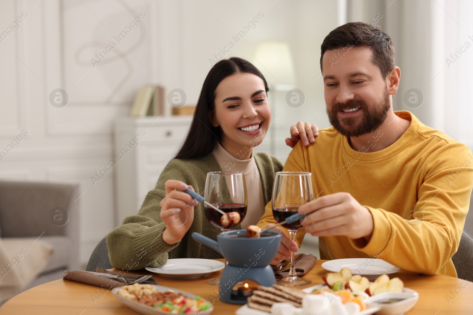 Photo of Affectionate couple enjoying chocolate fondue during romantic date at home