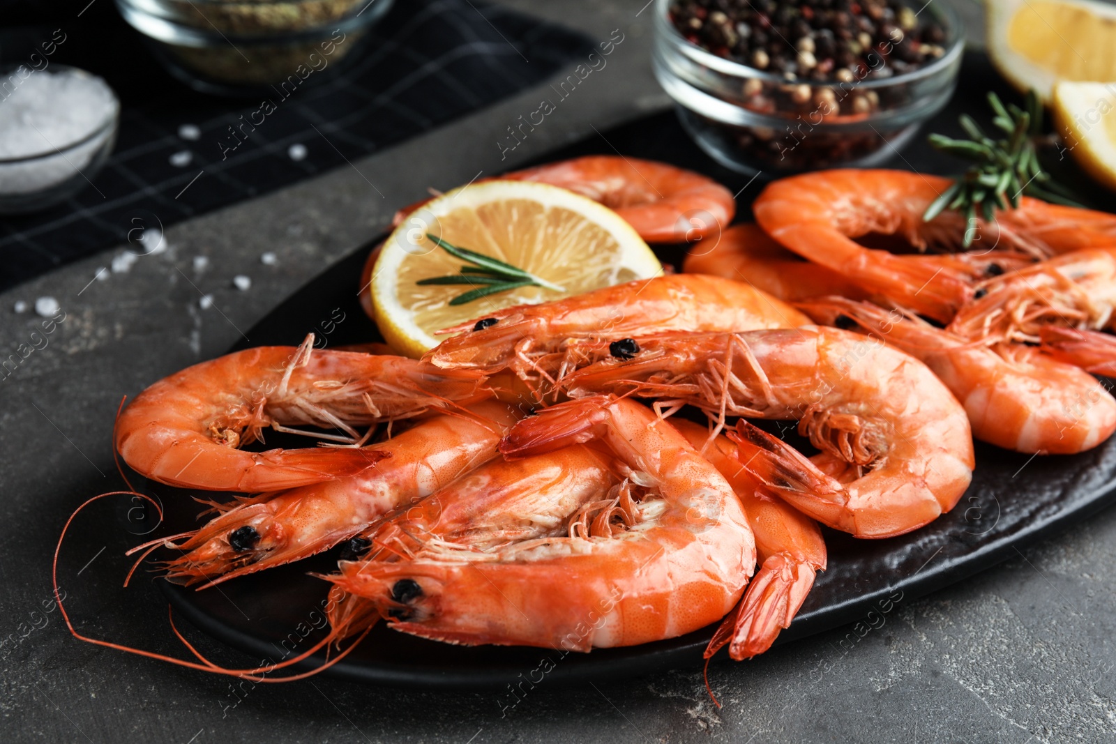 Photo of Delicious cooked shrimps with rosemary and lemon on dark grey table