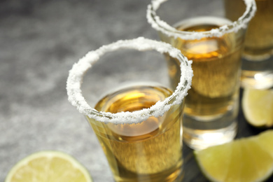Photo of Mexican Tequila shots with salt on grey table, closeup