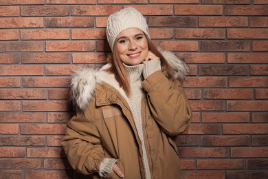 Photo of Young woman wearing warm clothes against brick wall. Ready for winter vacation