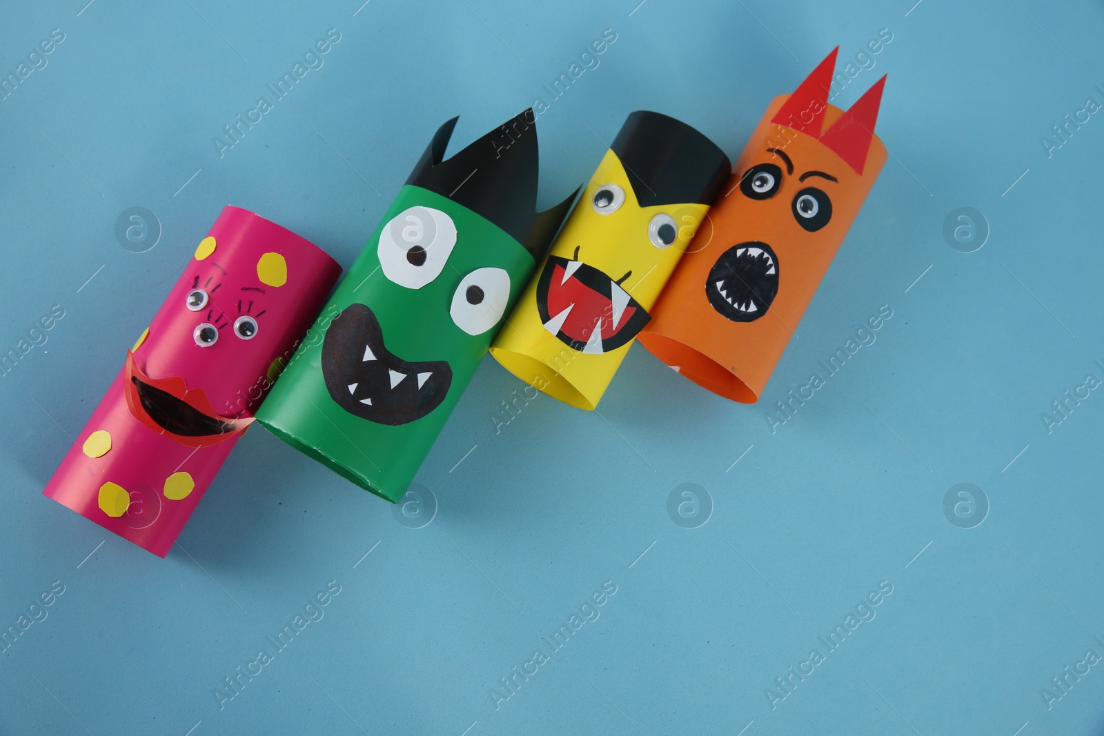 Photo of Funny monsters on light blue background, flat lay with space for text. Halloween decoration