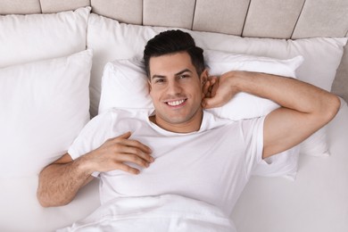 Photo of Happy man lying in bed at home, top view