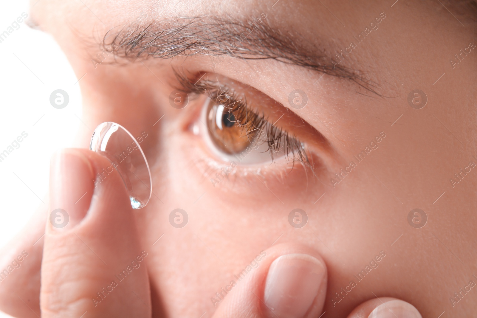 Photo of Young woman putting contact lens in her eye, closeup