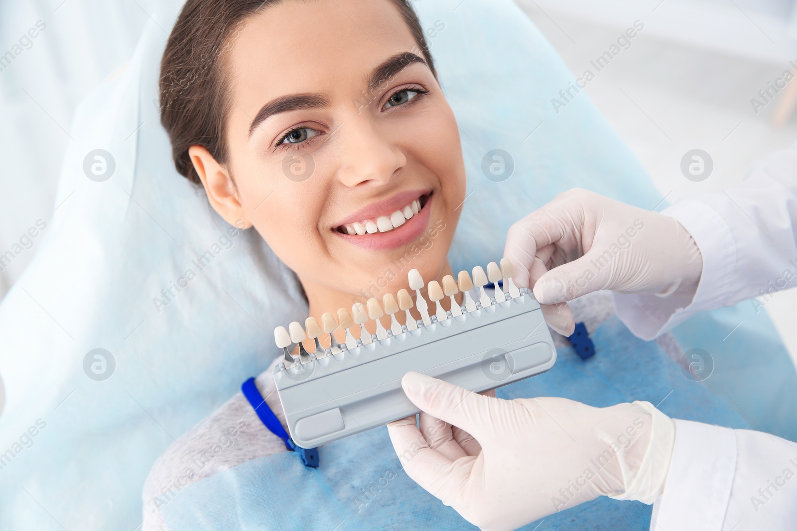 Photo of Dentist selecting patient's teeth color with palette in clinic