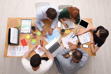 Photo of Team of employees working together at wooden table indoors, top view. Startup project