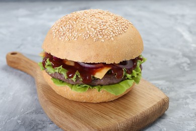 Delicious cheeseburger with lettuce, onion, ketchup and patty on grey table, closeup