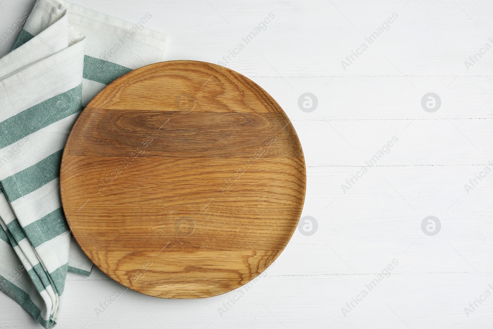 Photo of Empty wooden plate and napkin on white table, flat lay. Space for text