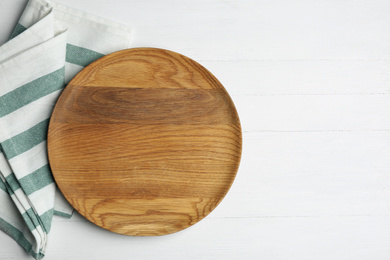 Photo of Empty wooden plate and napkin on white table, flat lay. Space for text