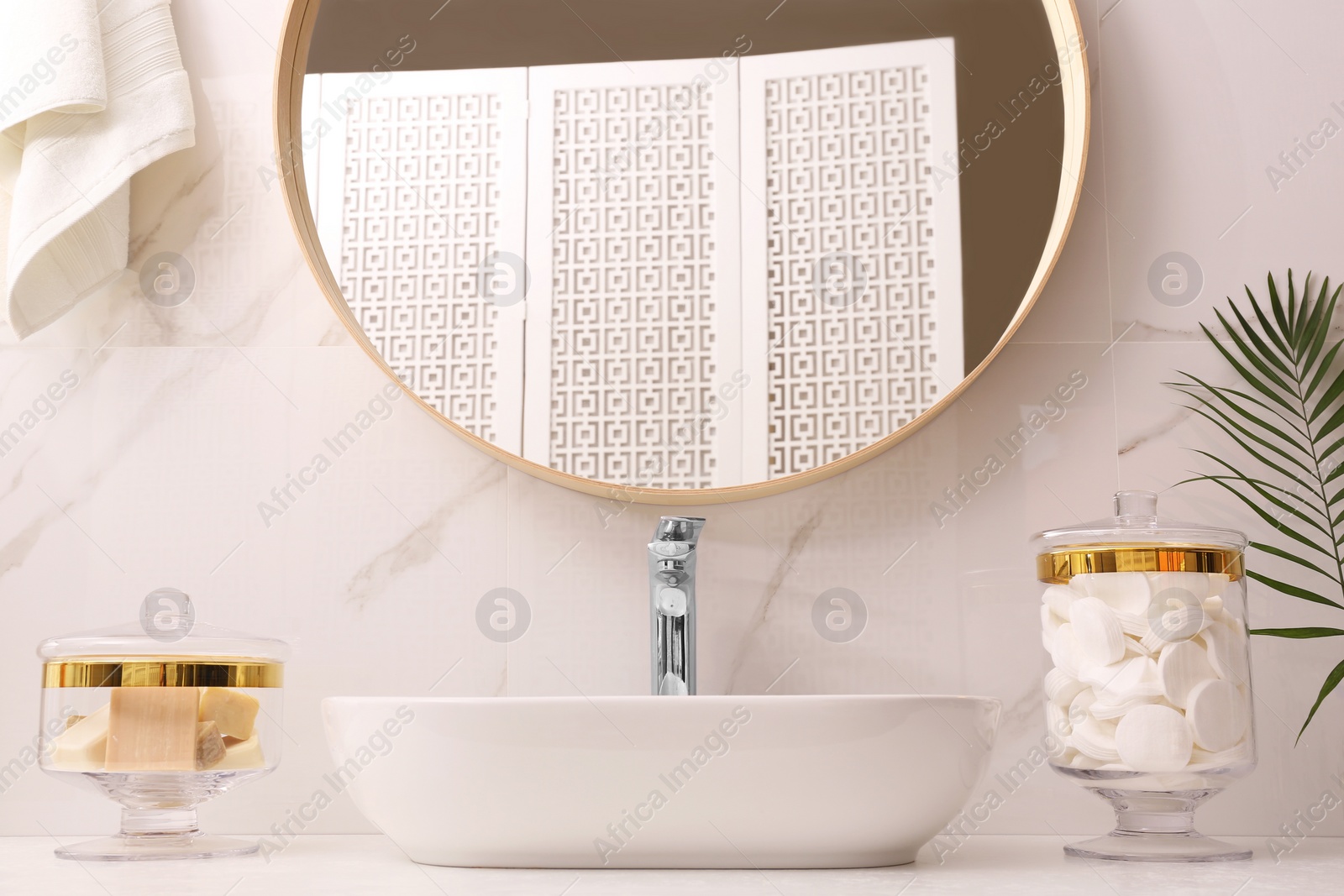 Photo of Glass jars with cotton pads and bars of soap on table in bathroom