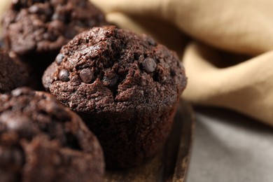 Photo of Board with delicious chocolate muffins on table, closeup