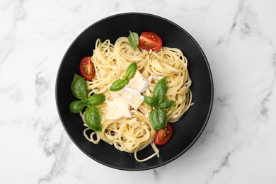 Photo of Bowl of delicious pasta with brie cheese, tomatoes and basil leaves on marble table, top view