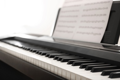 Photo of Modern piano with music sheets in room, closeup