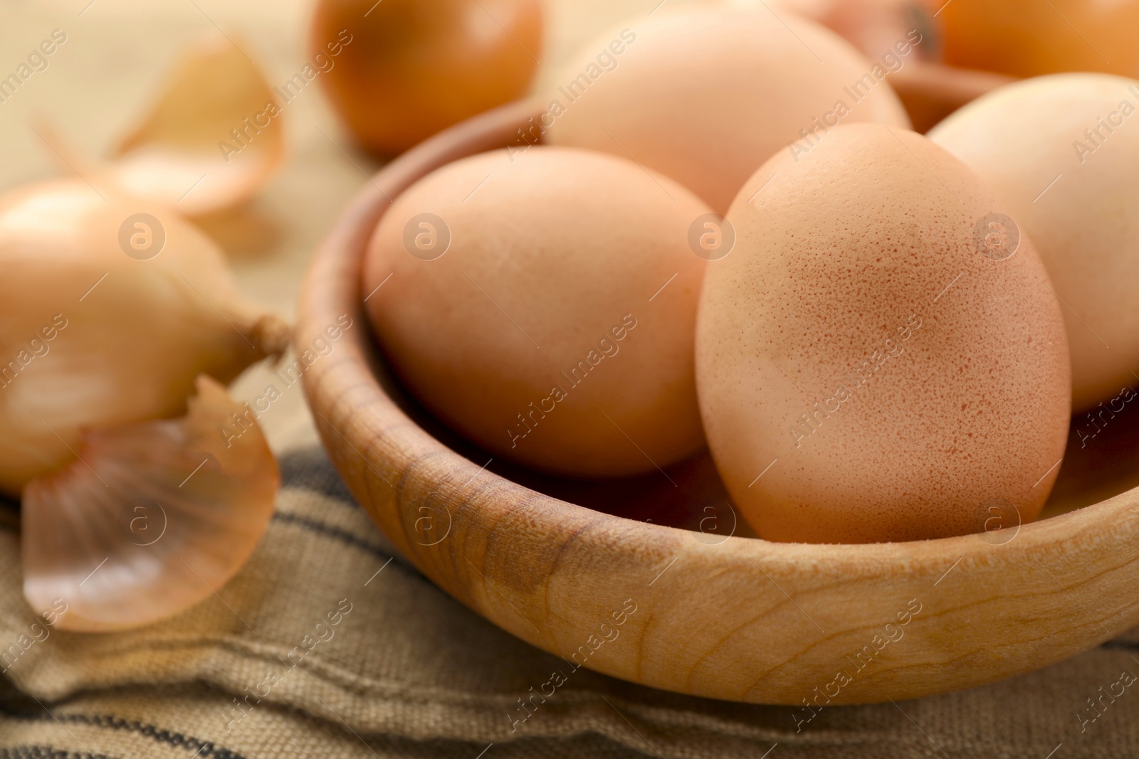 Photo of Easter eggs painted with natural dye in wooden bowl on table, closeup