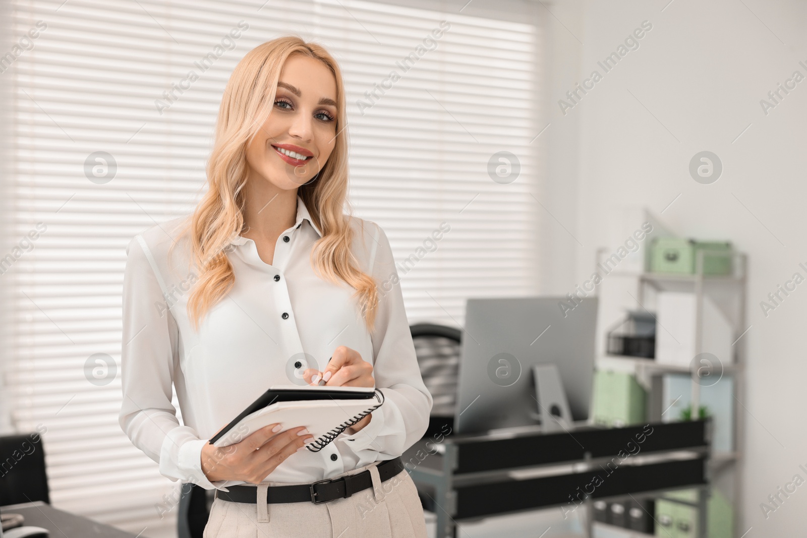 Photo of Happy secretary with notebook in office, space for text