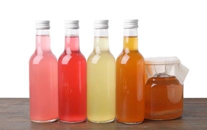 Photo of Delicious kombucha in glass bottles and jar on wooden table against white background