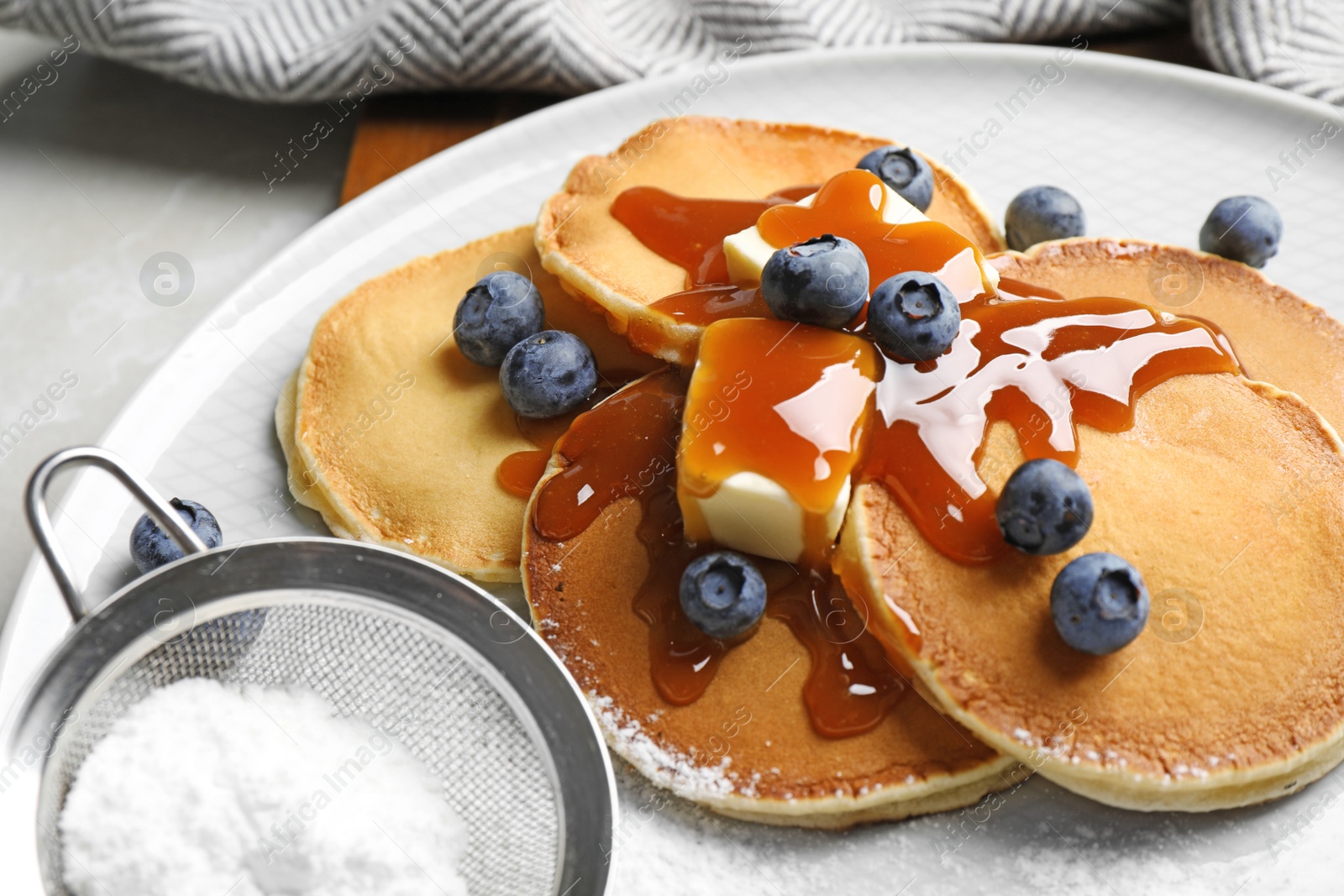 Photo of Delicious pancakes with fresh blueberries, butter and syrup on light grey table, closeup