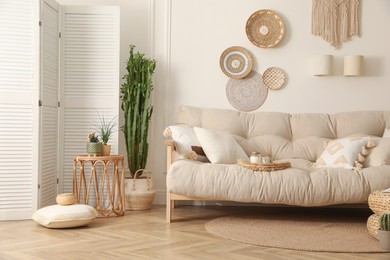 Stylish living room interior with comfortable wooden sofa and beautiful houseplants