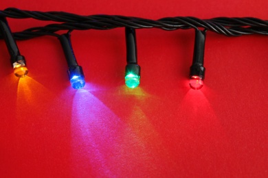 Photo of Glowing Christmas lights on color background, closeup