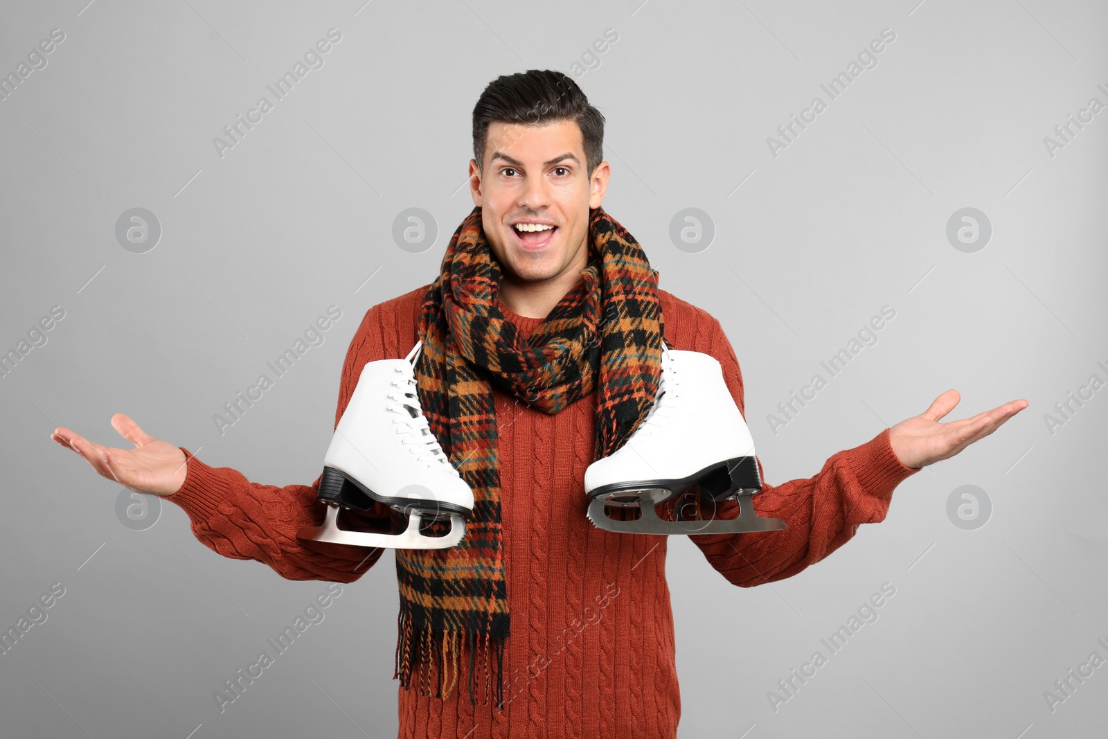 Photo of Emotional man with ice skates on grey background