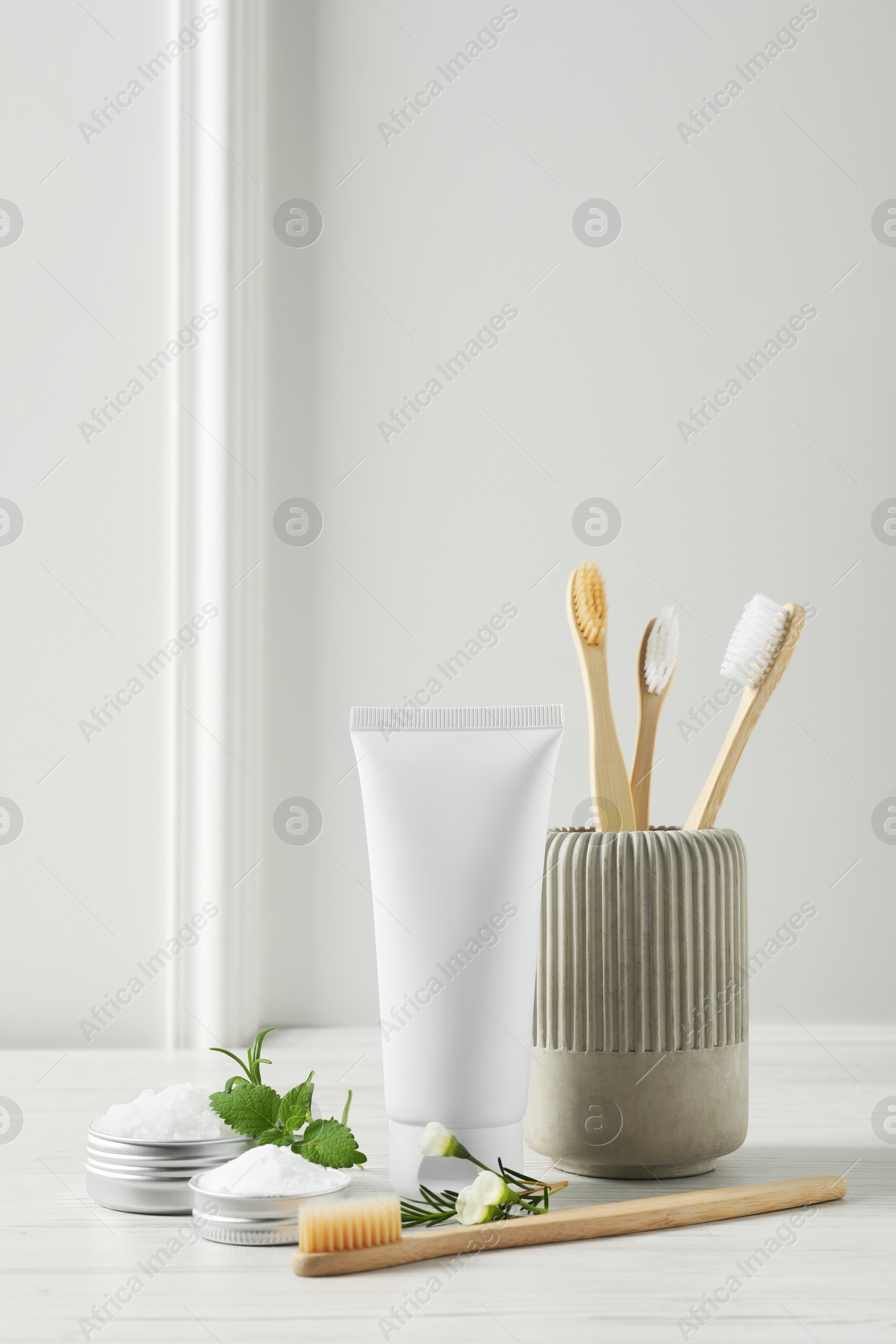 Photo of Toothbrushes, toothpaste and herbs on white wooden table