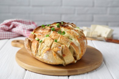 Photo of Freshly baked bread with tofu cheese and green onions on white wooden table