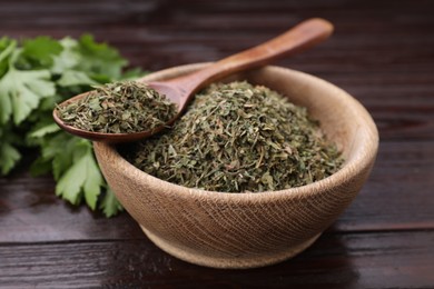 Photo of Dried aromatic parsley and fresh leaves on wooden table, closeup